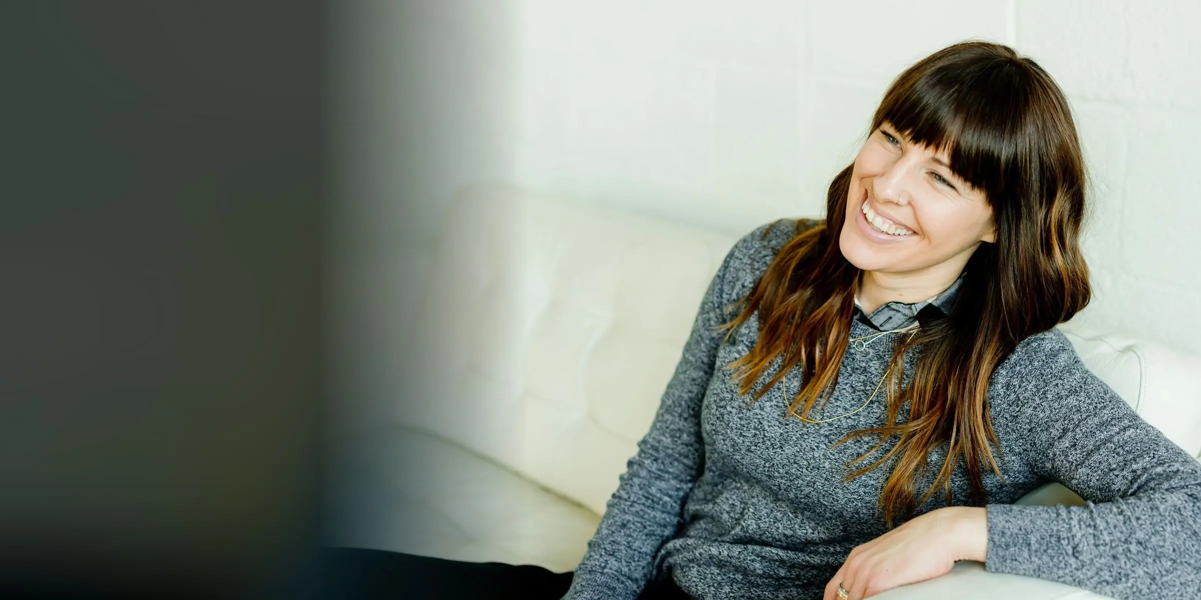 Une cliente souriante se détend sur son canapé, chez elle